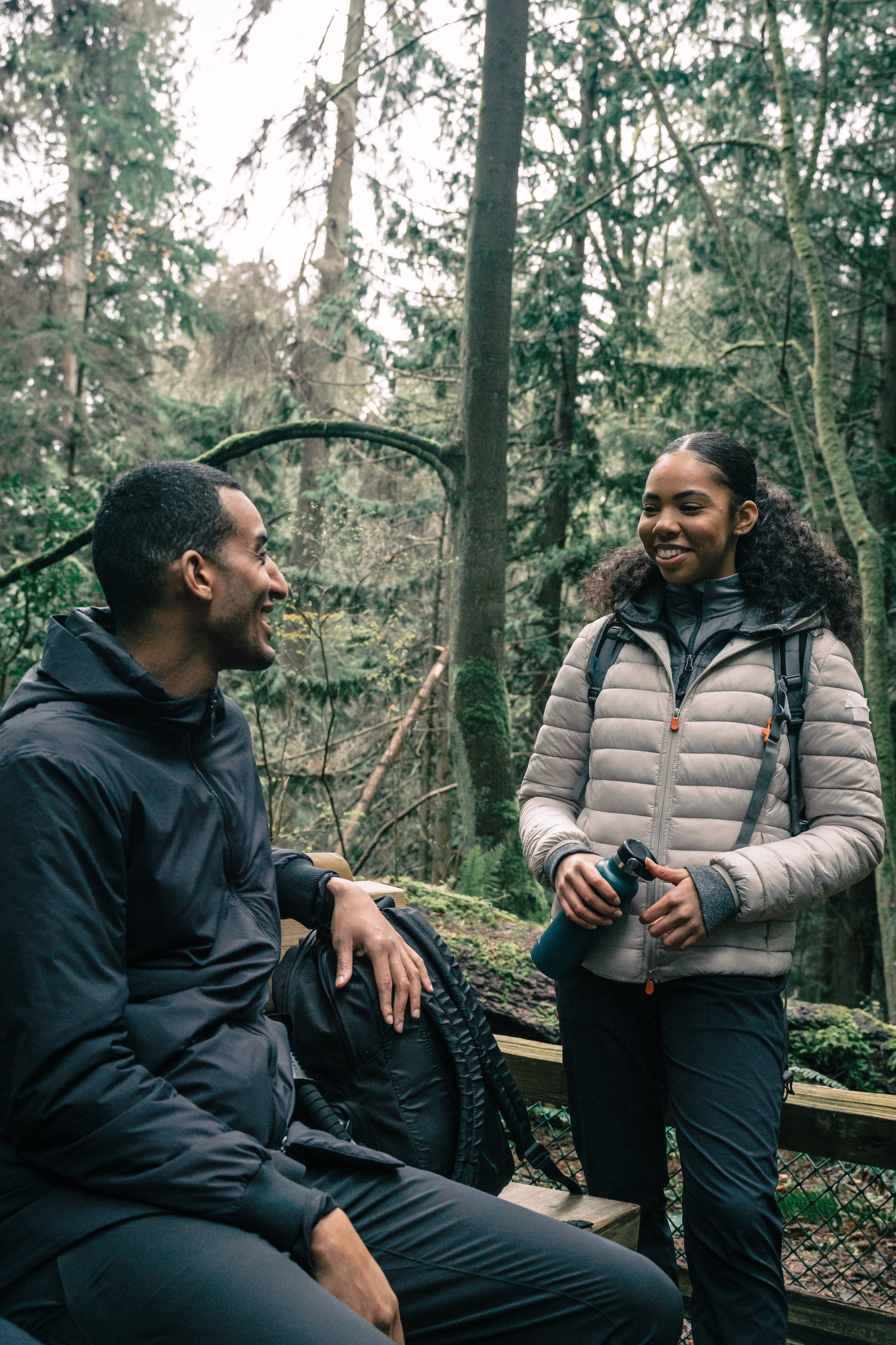 Two hikers talking on a forest footbridge