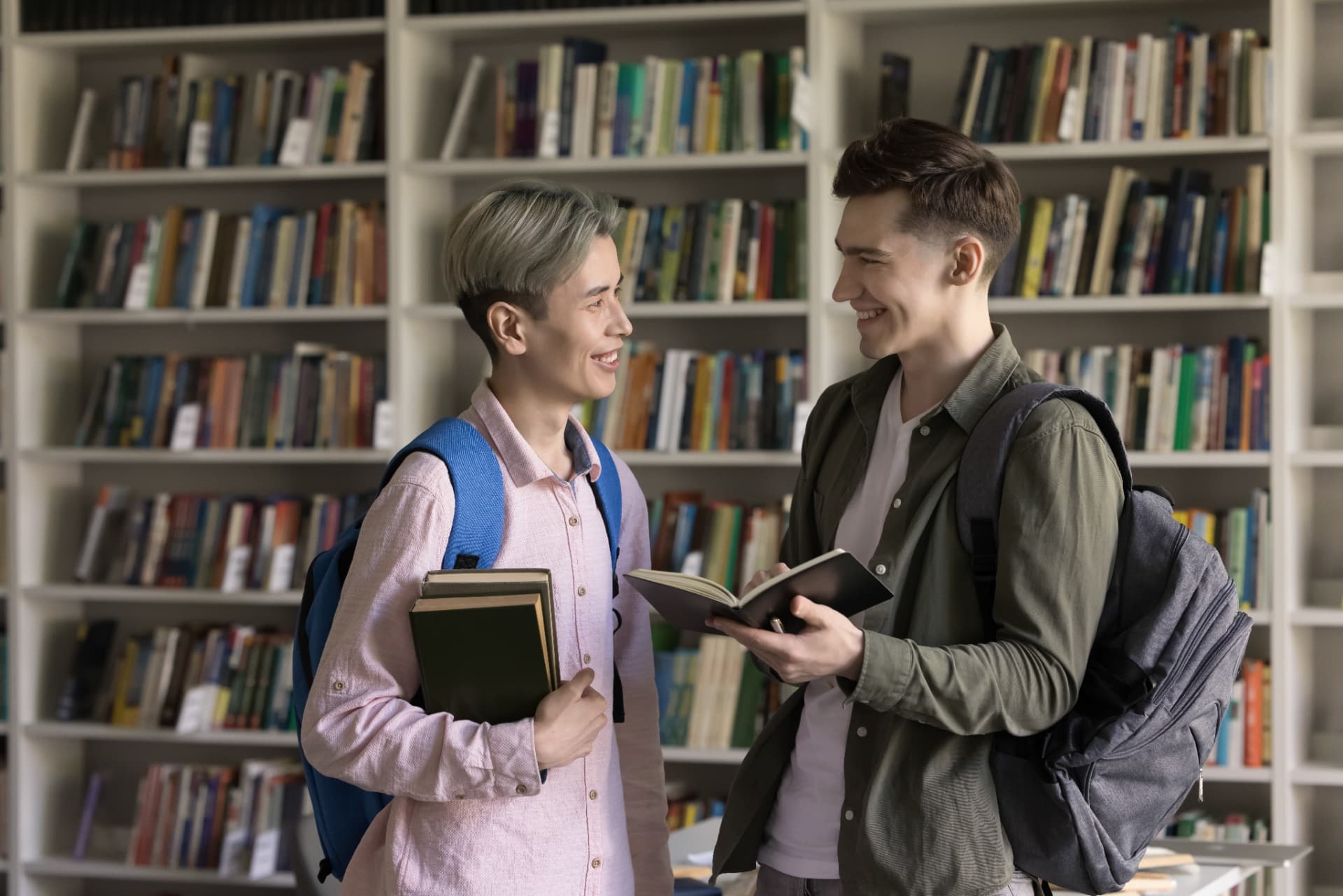 Two classmates laughing together in a library