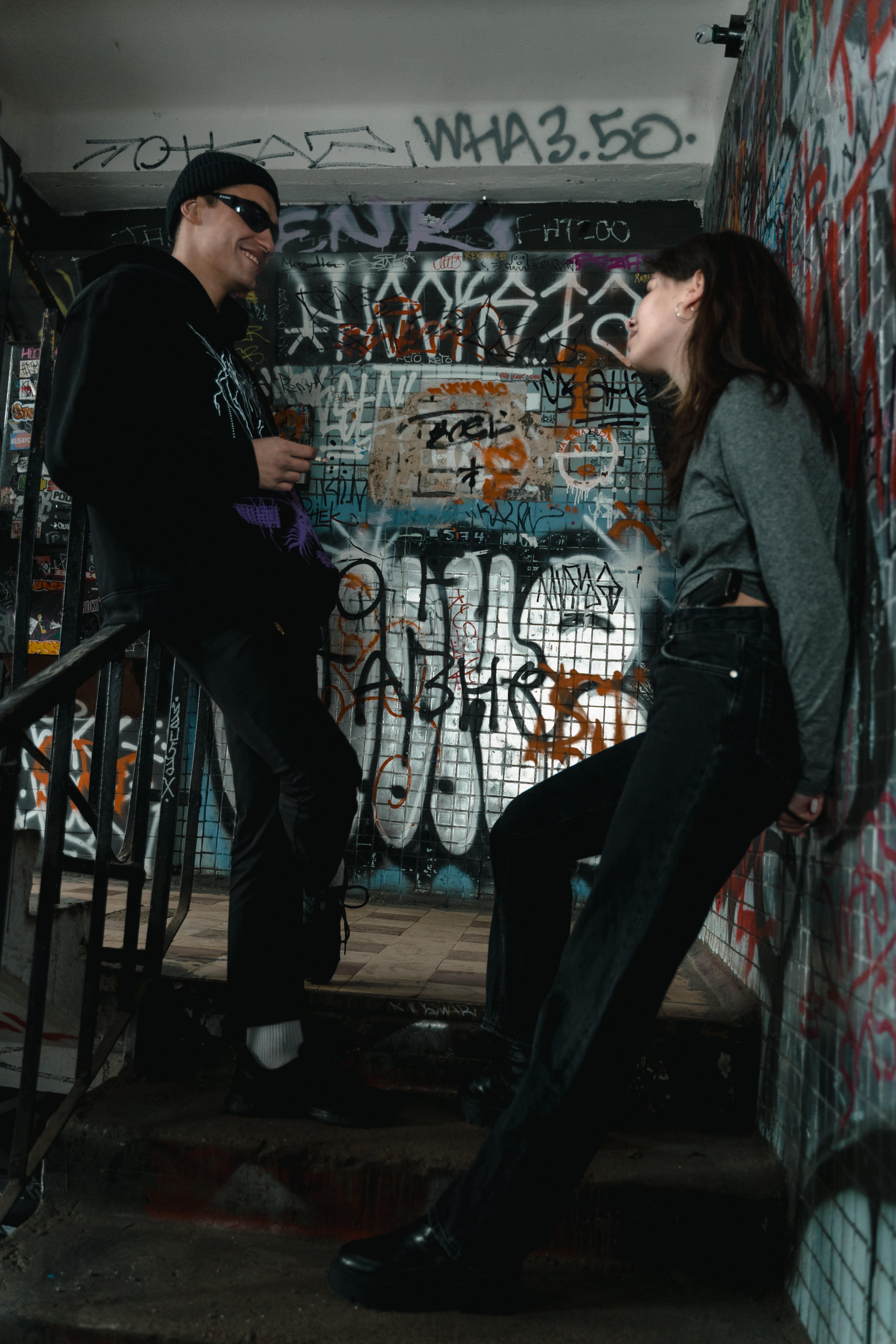 Two people talking on a graffiti-covered city stairwell
